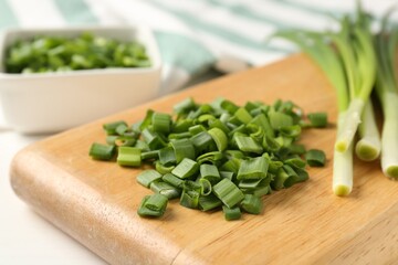Whole and cut fresh green onions on white table, closeup