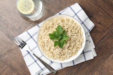 Delicious brown rice with parsley served on wooden table, top view