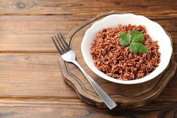 Delicious brown rice with parsley served on wooden table. Space for text