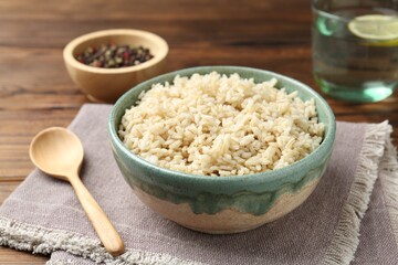 Delicious brown rice served on wooden table, closeup