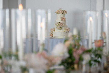 Three-tier wedding cake with blush roses framed by candlelit table