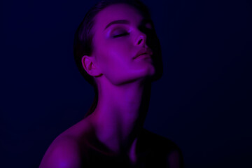 Fototapeta premium Serene young caucasian female in neon lighting with eyes closed