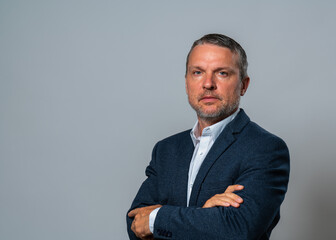 Middle-aged man with confident look in an elegant business suit with arms folded on his chest isolated on white background. image of successful professional. Business concept, career articles.