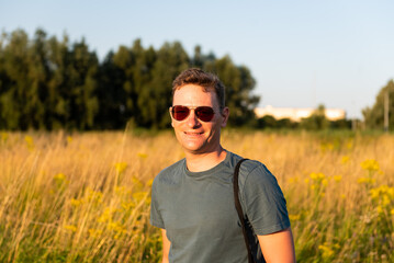 42 yo man with sunglasses, standing in the evening sun with a golden corn field in the background, Ghent, East Flanders, Belgium