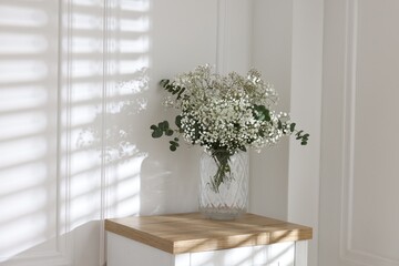Beautiful gypsophila flowers and eucalyptus branches in vase on table at home