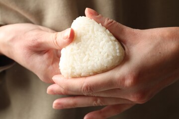 Woman with tasty onigiri (Japanese rice ball), closeup