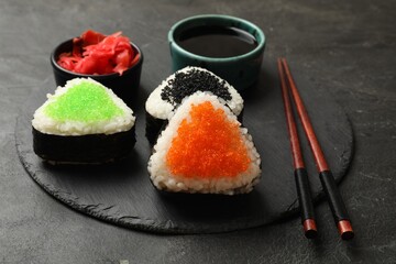 Tasty tobiko onigiri (Japanese rice balls) served on black table, closeup