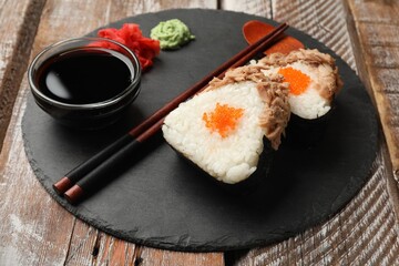 Tasty onigiri (Japanese rice balls) with tuna served on wooden table, closeup