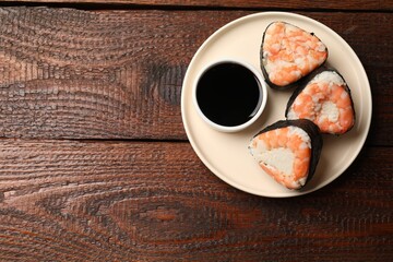 Tasty onigiri (Japanese rice balls) with shrimps and soy sauce on wooden table, top view. Space for text