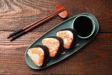 Tasty onigiri (Japanese rice balls) with shrimps served on wooden table, flat lay