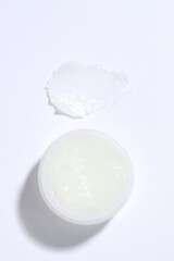 Moisturizing lip balm and jar on white background, top view