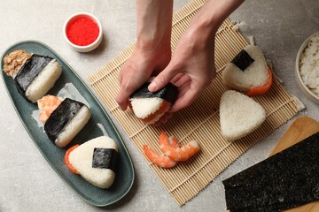 Woman making onigiri (Japanese rice balls) at light table, closeup