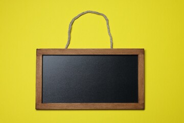 Blank small blackboard on yellow background, top view