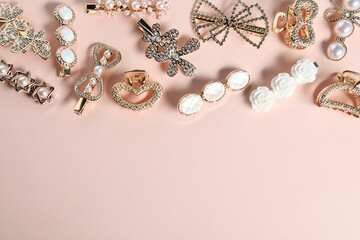 Different hair clips on pale pink background, flat lay. Space for text
