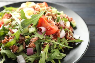 Delicious salad with brown rice on black wooden table, closeup