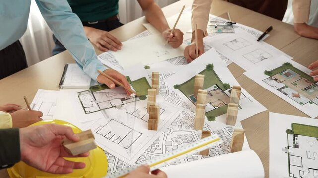 Architect and safety engineer discussion about building construction use blueprint on table with architectural document, measurement tool and wooden block scatter around at modern office. Delineation.