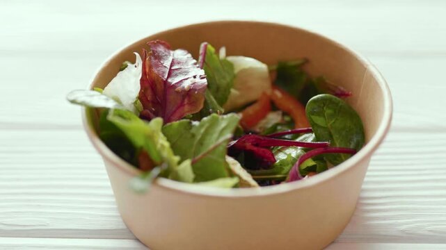 Closeup of man eating a fresh healthy salad from a zero waste container to go. Food delivery, healthy food concept.
