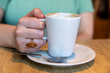 Female hands with a ring holding a coffee cup