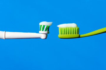 New electric automatic and manual toothbrushes with toothpaste on a blue background on the same level.