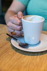 Female hands with a ring holding a coffee cup