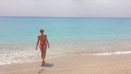 A Woman in a Red Bikini Walking into the Turquoise Waters of the Ocean