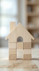 Wooden house model on table, bright interior background, home building concept, real estate