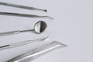 Collection of dental instruments on a light background. Dental mirror, tweezers and several hooks used in the treatment of various diseases of the teeth and gums. Diagnostic dental instrument set
