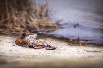 Natural background with knitted scarf lying on the shore, atmospheric photo.