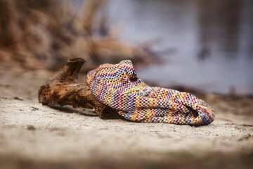 Natural background with knitted scarf lying on the shore, atmospheric photo.