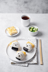 Rice ball onigiri with filling in the form of chicken with funny faces and with tamagoyaki in a plate