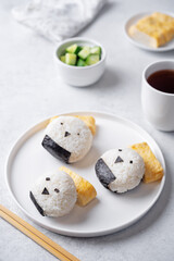 Rice ball onigiri with filling in the form of chicken with funny faces and with tamagoyaki in a plate
