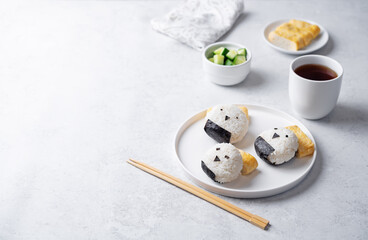 Rice ball onigiri with filling in the form of chicken with funny faces and with tamagoyaki in a plate