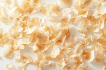 A close up view of scattered coconut flakes showing their texture and light brown color on white surface
