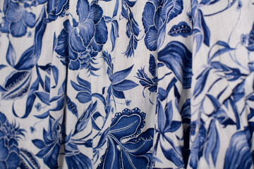  A close-up of blue floral fabric with intricate white designs, perfect for fashion and decor.