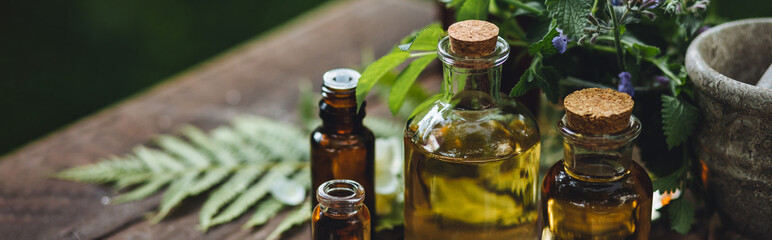 Natural organic essential oil in small glass bottles on wooden background. Homemade production for spa, sauna, bath. Relaxation, alternative medicine, remedy, naturopathy, pure ingredients
