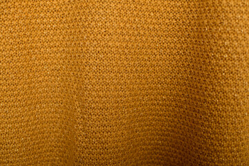 A macro shot of golden knit fabric, capturing its fine details and warm color.