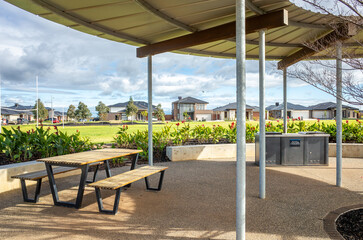 A sheltered picnic area with modern bench seating offers a community gathering spot, and a...