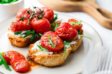 Bruschetta with cottage cheese, arugula and roasted cherry tomatoes. Food photo.