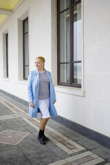 Obraz premium A woman in a coat walking in the park. Stylishly dressed blonde