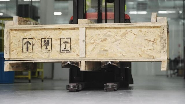 Industrial forklift transporting wooden cargo crate in a warehouse environment