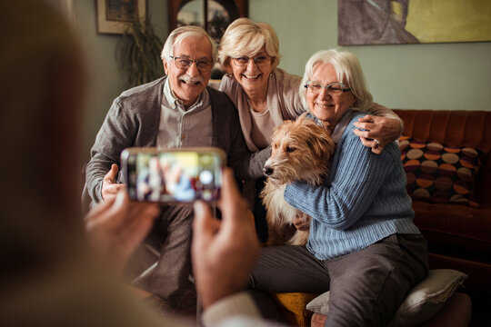 Happy senior friends spending time together with dog at home