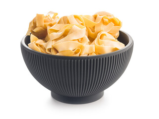 Italian pasta tagliatelle. Uncooked noodle pasta in bowl isolated on white background.