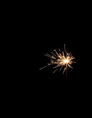 A single sparkler burns brightly against a pure black backdrop, holiday, background image