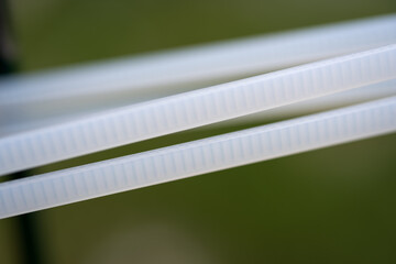 Close-Up of White Zip Ties on Metal Rod
Two white plastic zip ties fastened around a dark green...