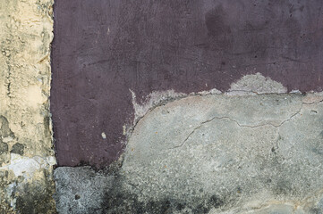 A weathered concrete wall with dark stains and peeling paint, showcasing an aged texture. The rough...
