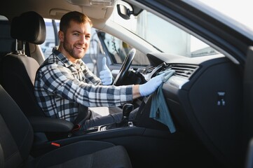 Car detailing and car wash concept. Young man, car wash worker, wearing protective rubber gloves,...