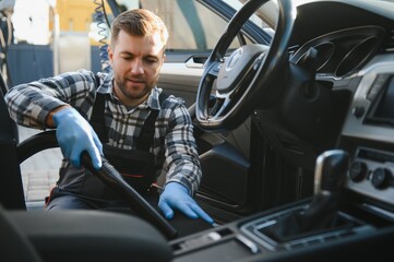 Car detailing and car care concept - Professional using steam vacuum for draining stains