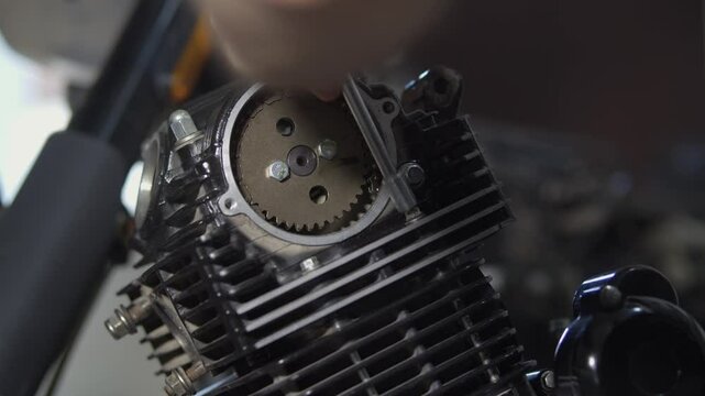 A mechanic repairs a motorcycle engine using a torque wrench to check the tightness of the bolts on the engine