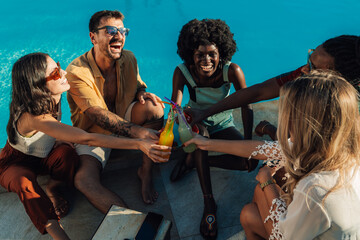 Friends toasting colorful drinks at poolside summer party
