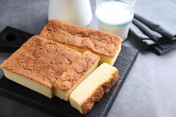 Tasty Japanese Castella sponge cake and milk on grey table, closeup. Space for text